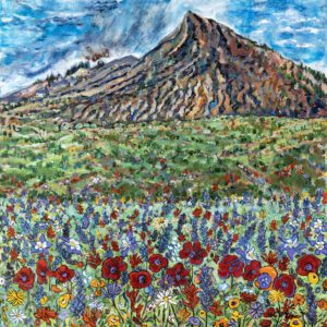 Wildflowers in fields with hiking trails and Crested Butte mountain and blue skies in the background.
